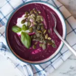 Eine Schüssel Rote Beete Gazpacho garniert mit frischen Kräutern.