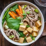 Delicious miso soba noodle soup with tofu and fresh vegetables in a bowl.