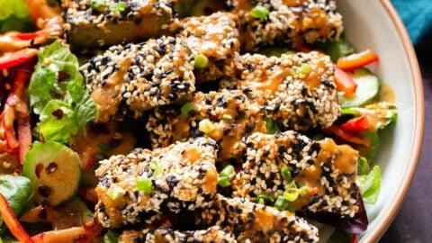 Crispy Sesame Tofu Bowl drizzled with peanut sauce and fresh vegetables.