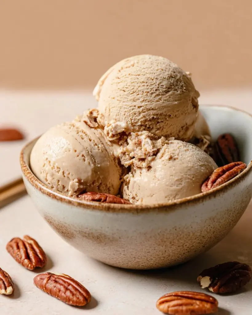 Vegan maple butter pecan ice cream served in a bowl with pecans on top.